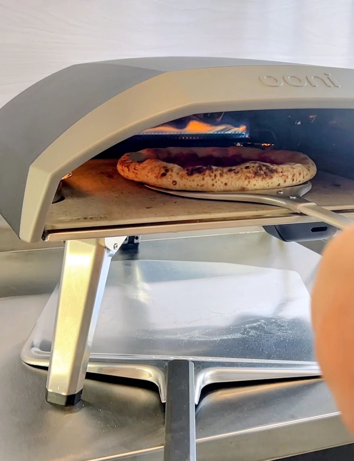 Pizza precocida terminando de hornearse en el horno Ooni