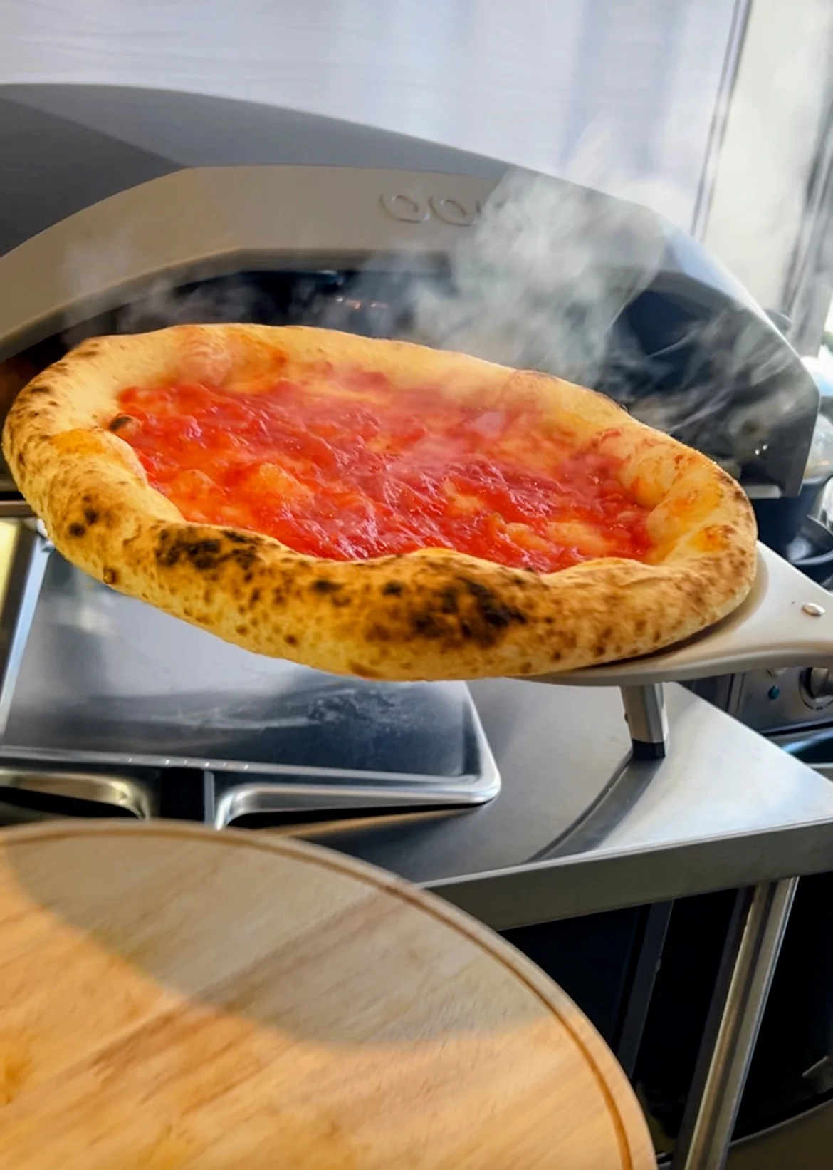 Pizza recién salida del horno, con salsa pomodoro y vapor